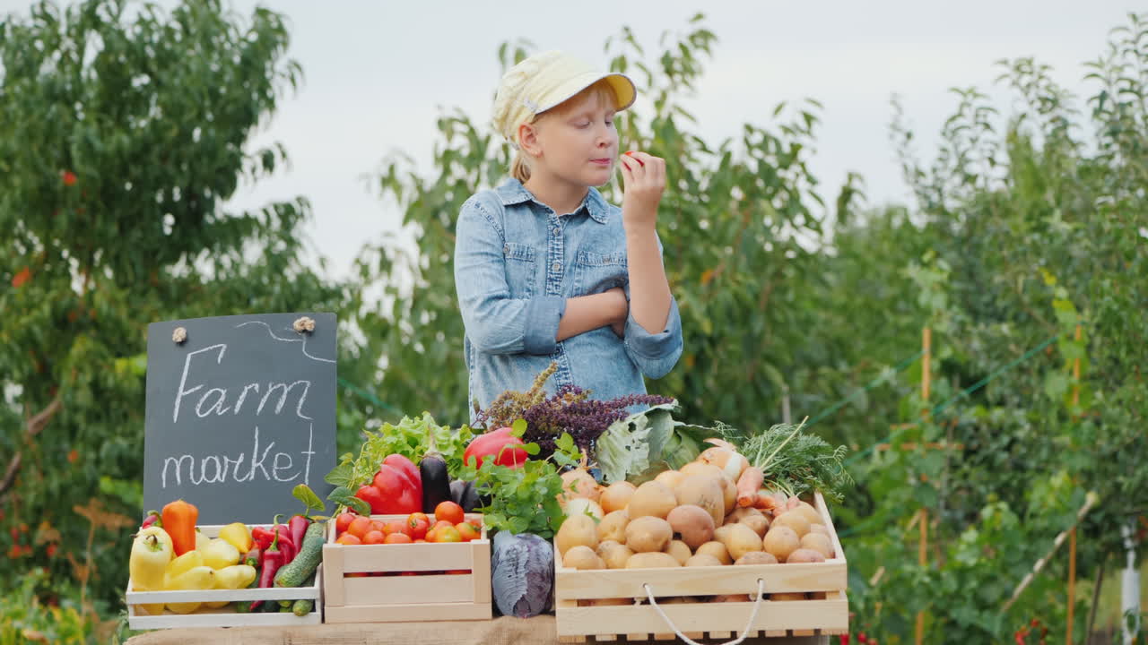 카운터 맛있는 조직에서 그녀의 야채를 먹는 농민 시장에서 어린 소녀 판매자