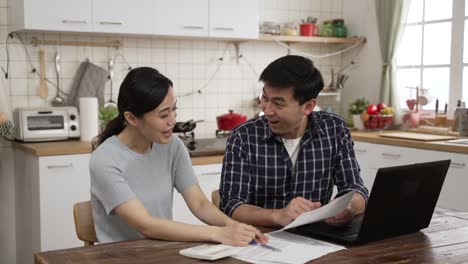 worried asian husband and wife examining tax bills and calculating spending with a calculator at home. the man feeling shocked about going over budget