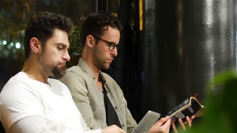 clientes leyendo revistas y usando tabletas digitales mientras esperan