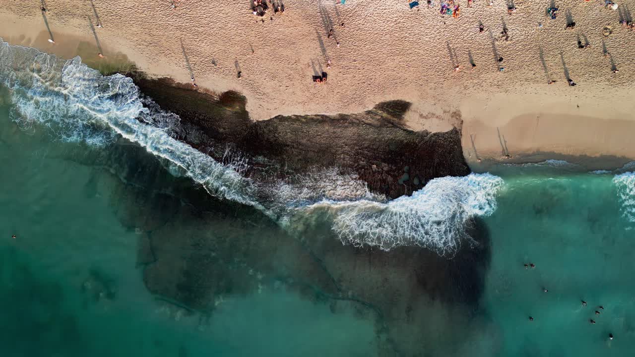Peaceful evening at Dreamland Beach Bali filmed from above, featuring golden sand, calm ocean water, and warm tropical ambiance as the sun descends over the southern shore