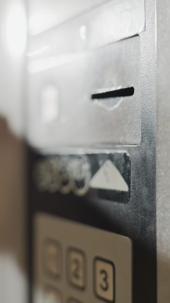 Close-up of hand inserting key into digital safe lock panel, attempting to access secured storage or safe, with keypad and metal surface in view