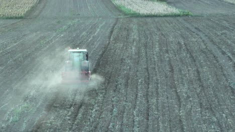 toma aérea de seguimiento del campo agrícola del tractor arando y haciendo polvo
