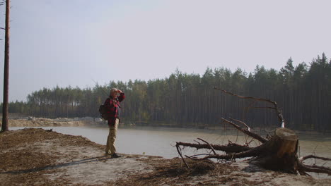 pescador está mirando a su alrededor en el lago del bosque admirando la naturaleza en la temporada de otoño lugar de pesca y relajarse