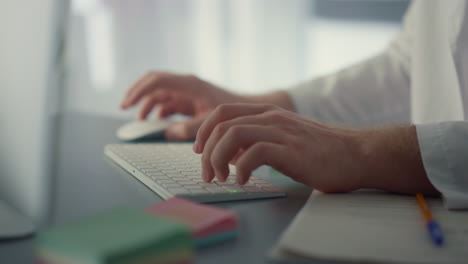 las manos del médico usando el teclado de la computadora en el hospital de cerca. el médico trabajando.