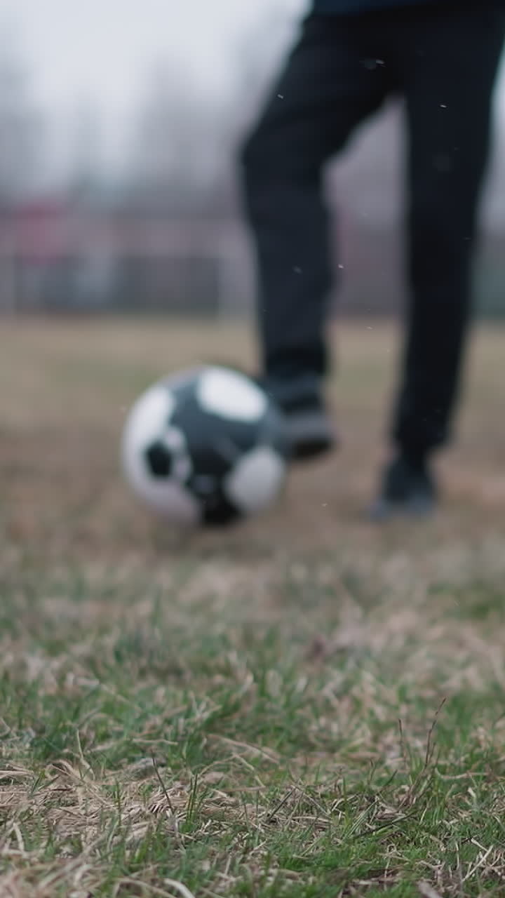 Blurred close-up of someone passing a football to another person who stops the ball, as he walks away, the background features a blur grassy field