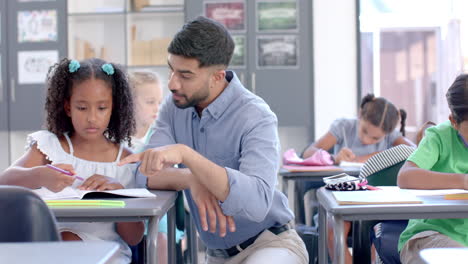 young teacher assists a biracial girl in a classroom setting at school