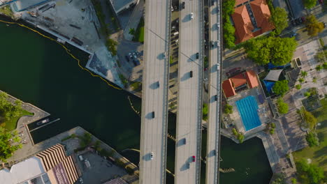 Vehicles-driving-on-elevated-highway-above-city,-multilane-bridge-over-Miami-river.-Birds-eye-view-in-golden-hour.-Miami,-USA