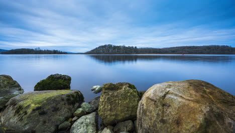 Time-lapse-of-a-rocky-shore-foreground-with-forest-in-distance-on-a-cloudy-sunny-day-at-Lough-Key-in-county-Roscommon-in-Ireland