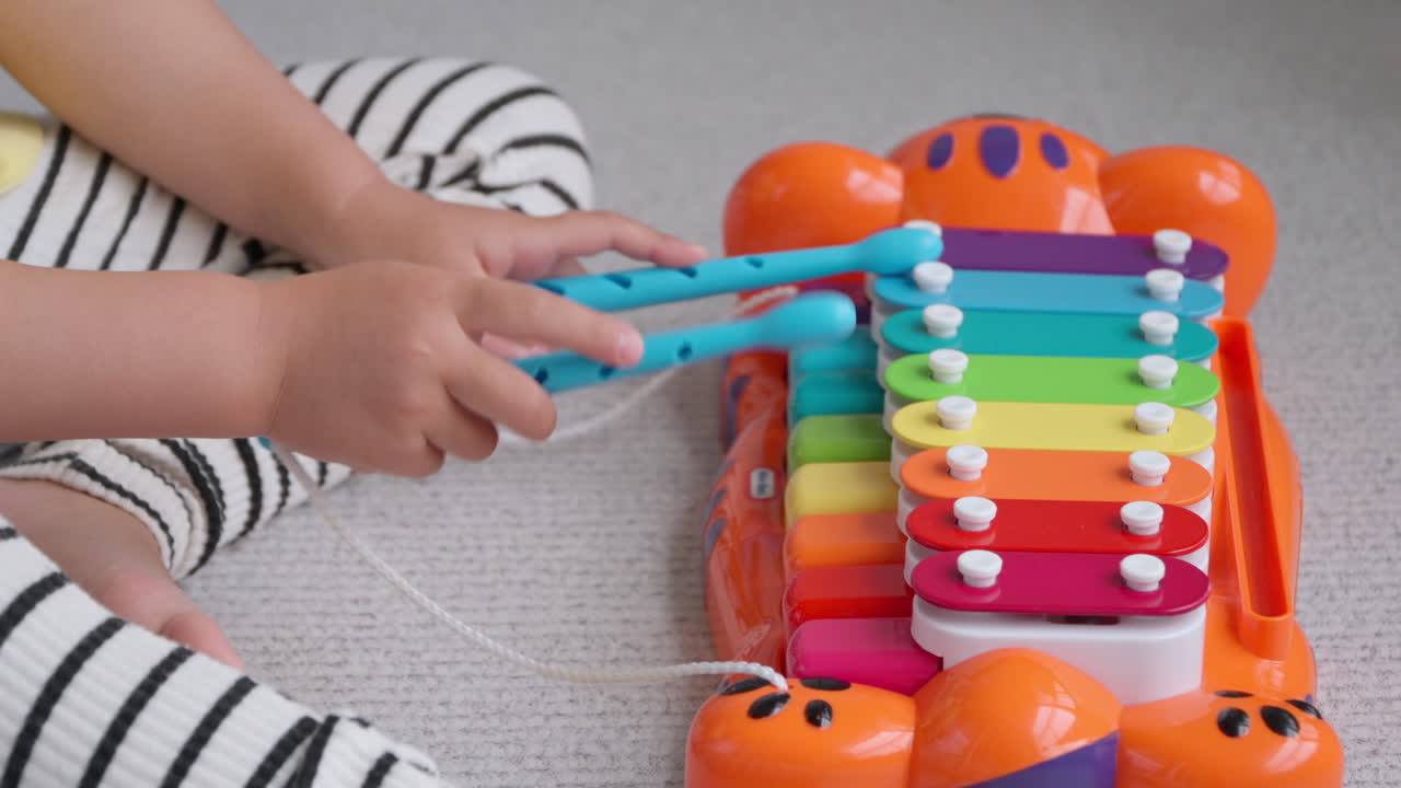 Little Girl's Hands Playing on Toy Piano Tikes Jungle Jamboree Tiger Xylophone At Home Sitting on Floor - close up slow motion
