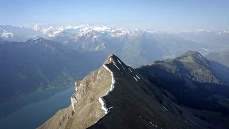 a hiking path on beautiful ridge top amongst huge mountains and above a green valley with a blue lake