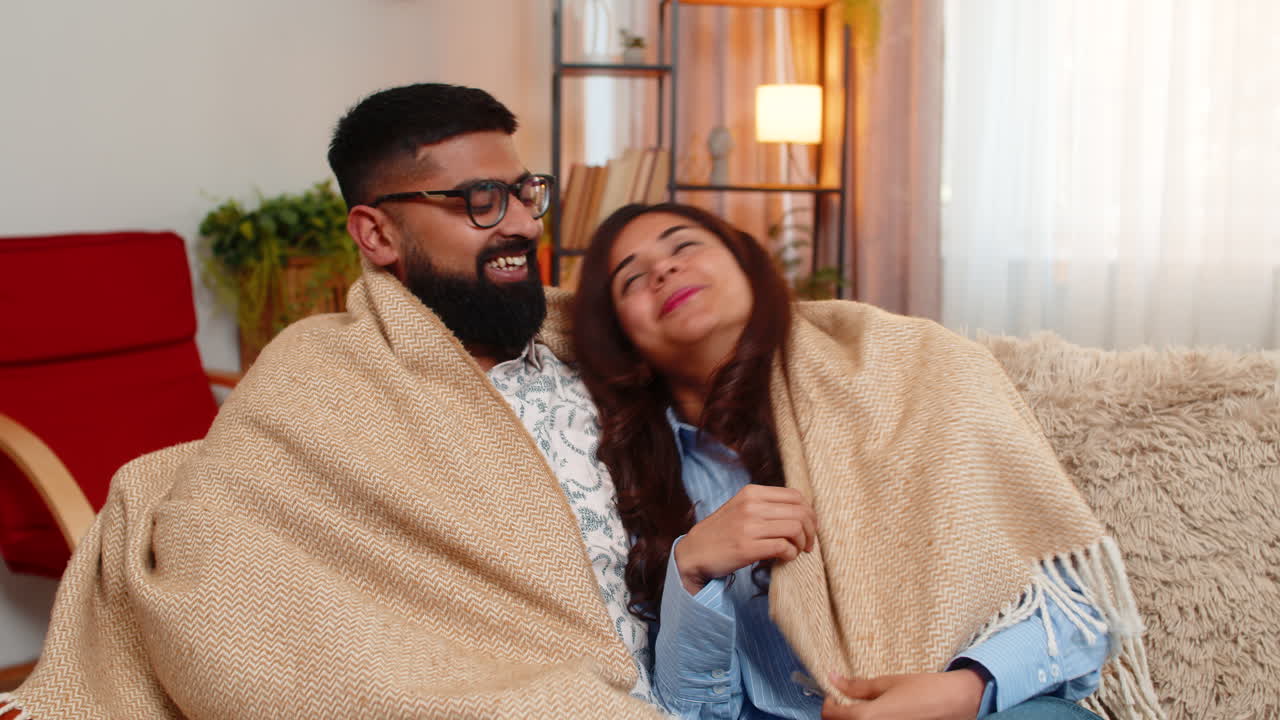 Indian family couple man woman cuddling under blanket at home enjoying silence cozy peaceful moment