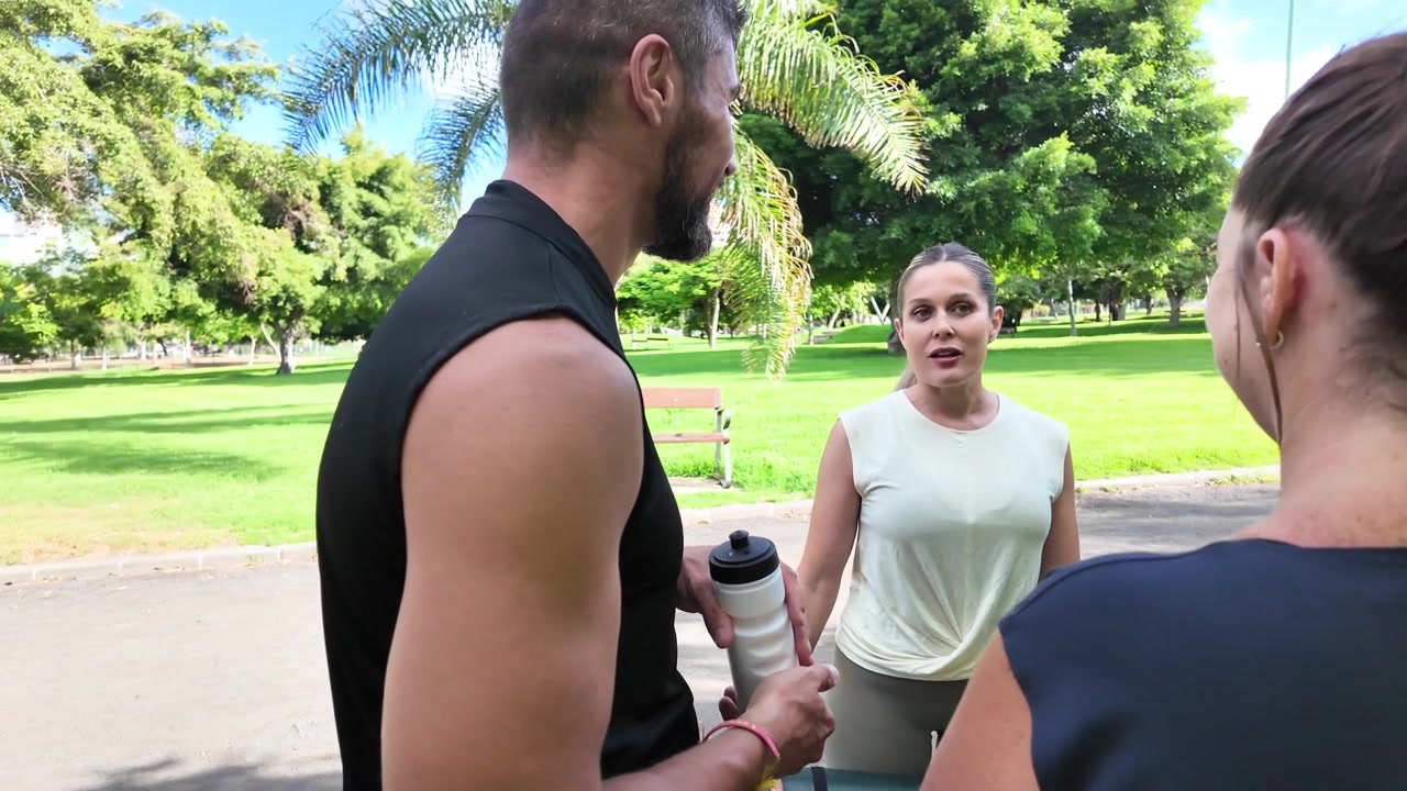 Grupo de amigos deportistas conversando después de entrenar en el parque