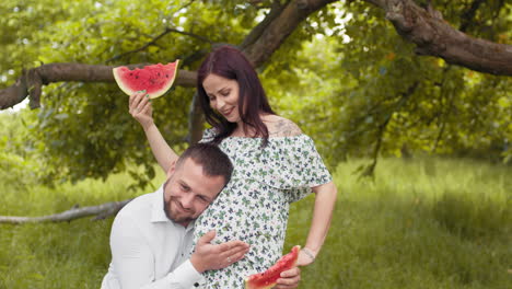 pregnant couple enjoying watermelon in the park