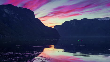 Brilliantly-colorful-sunset-time-lapse-at-a-mountain-fjord-in-Norway-as-the-water-shifts-with-the-tide,-wind-and-currents