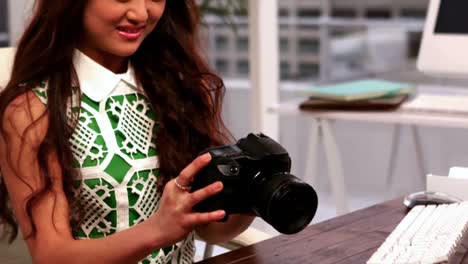 appy photographer sitting at her desk holding her camera