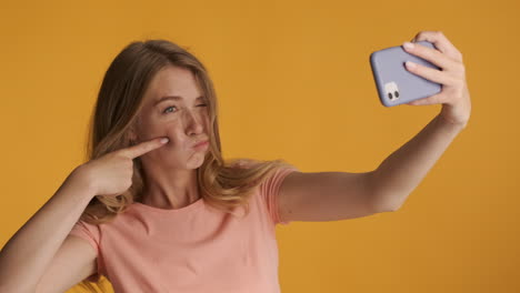 una mujer caucásica tomando selfies con su teléfono inteligente.