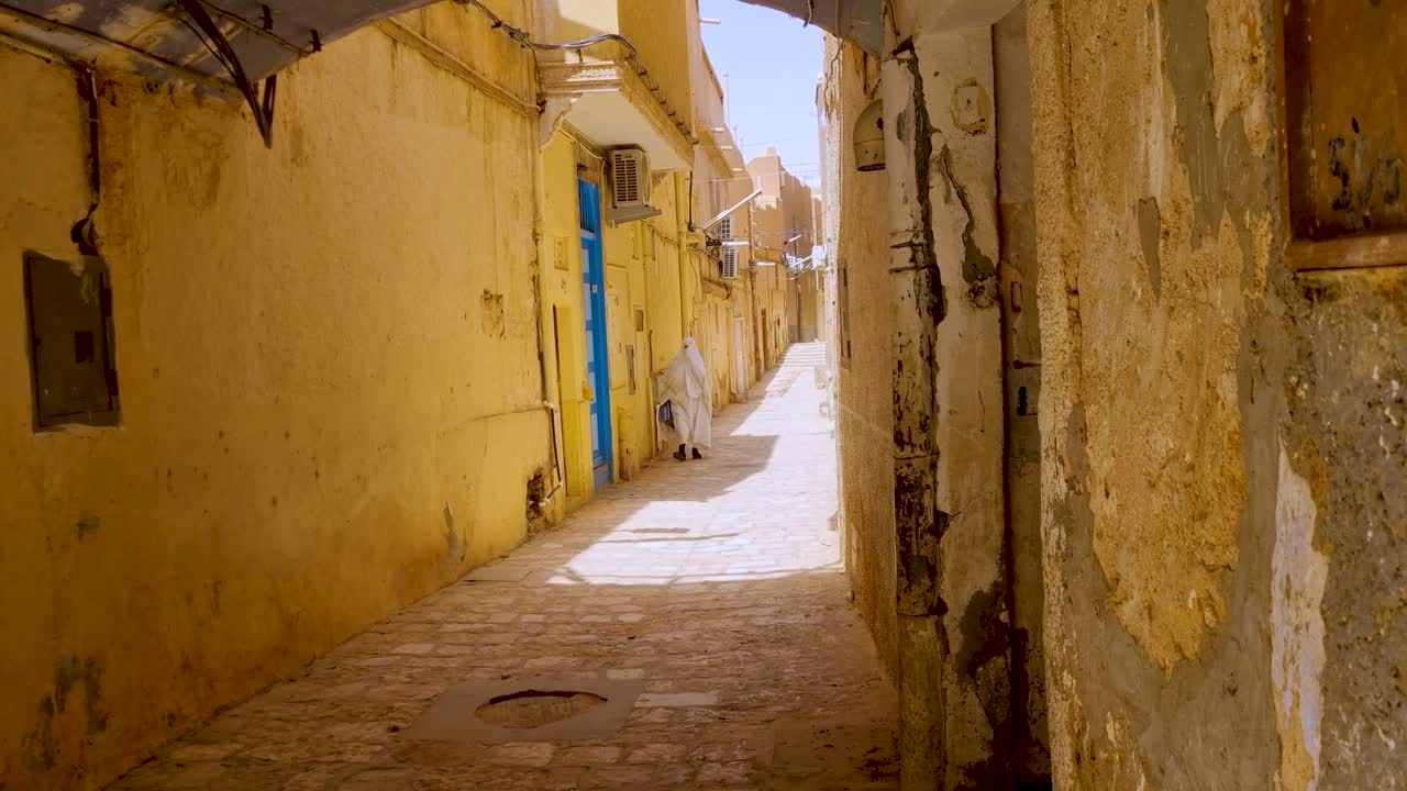 Walking through a narrow, sunlit street in a historic North African city