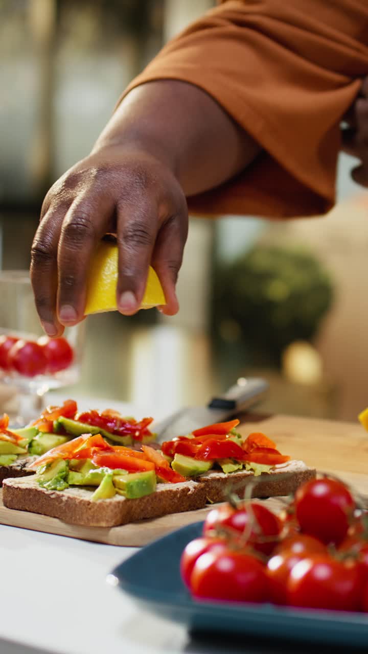 Video verticale: donna afroamericana che spremi il succo di limone sull'avocado per una ricetta di toast.