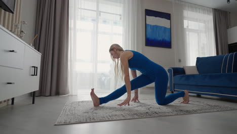 permaneciendo en casa en cuarentena y trabajando remotamente desde casa una mujer entrena y hace ejercicios de equilibrio mientras está de pie en la alfombra. ropa deportiva haciendo ejercicio quemando grasas calorías entrenamiento de fuerza