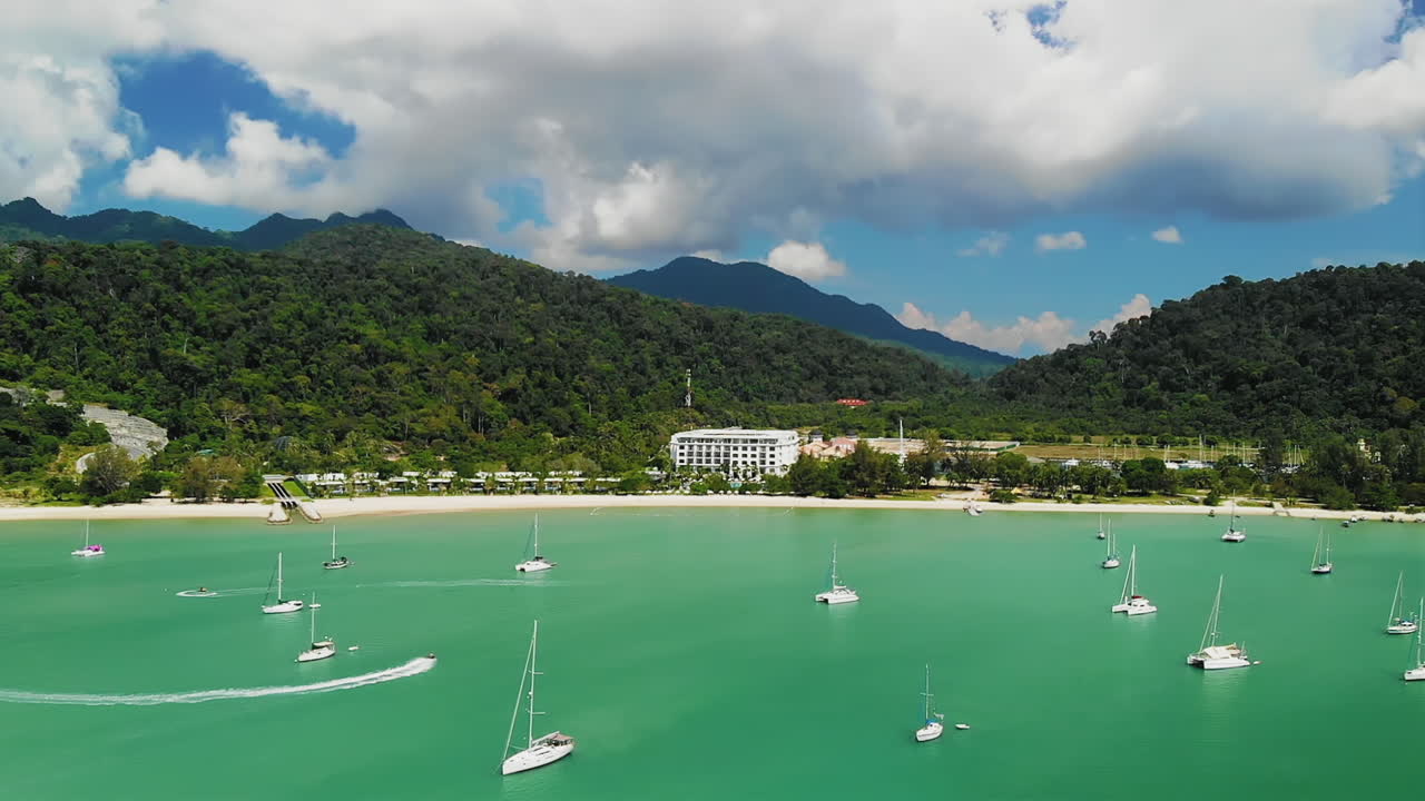 고급 관광 리조트 근처의 범선 사이에서 제트 스키 타기