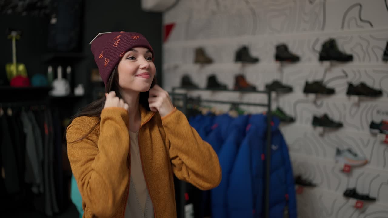 mujer sonriente probándose un nuevo y colorido sombrero de invierno en una tienda.