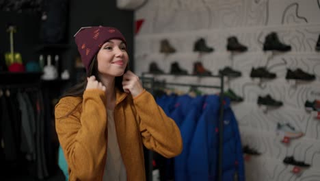 smiling woman trying on a new colorful winter hat in a store