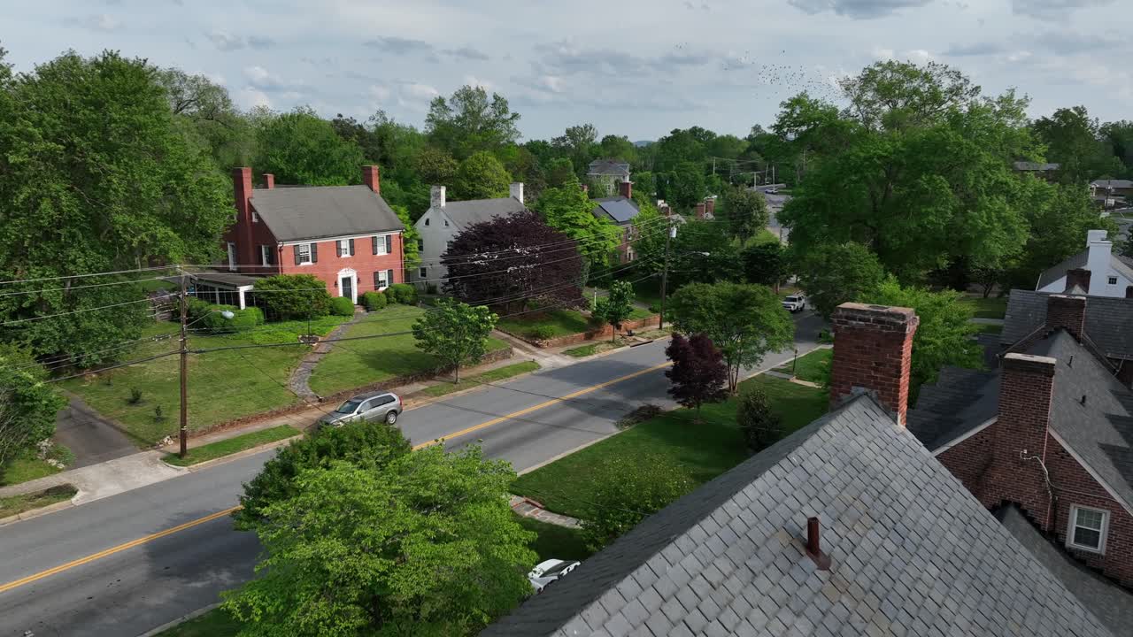 American houses with double chimney in suburb district of Virginia. Sunny day in calm spring season. Aerial forward wide shot. Red brick homes and car on street.