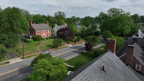 american houses with double chimney in suburb district of virginia. sunny day in calm spring season. aerial forward wide shot. red brick homes and car on street.