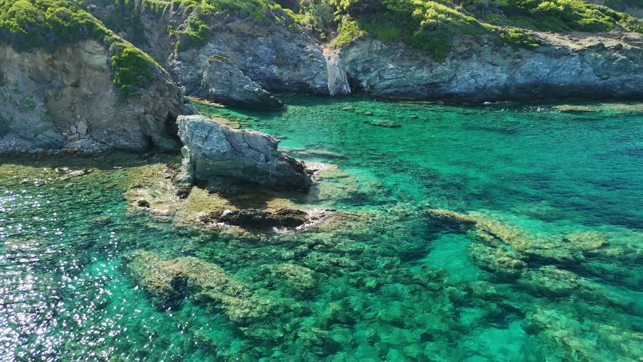 바위가 있는 해안선과 함께 은 푸른 물, 위에서 자연의 아름다움을 포착하는 공중 풍경