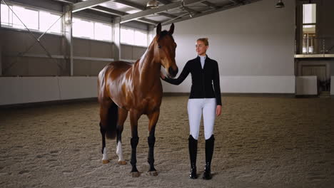 woman with a horse in an indoor riding arena