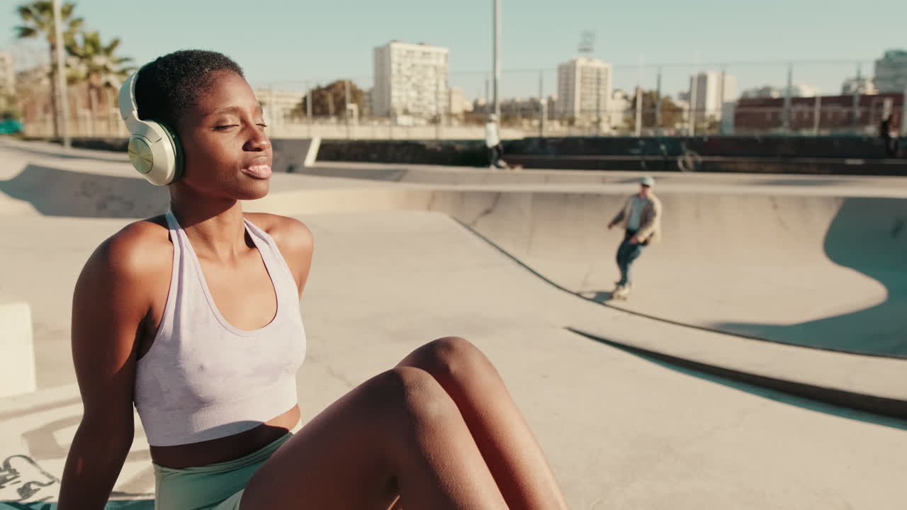 Young Black Woman Relaxing and Listening to Music in a Skate Park