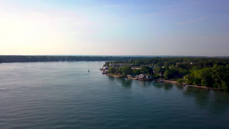 aerial flying over the water toward a picturesque small town on a sunny, summer morning