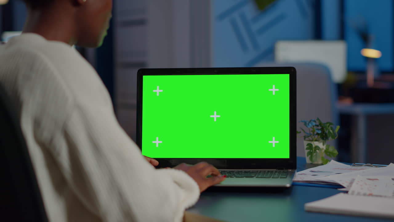 Freelancer di colore che cerca usando un laptop con display a schermo verde.
