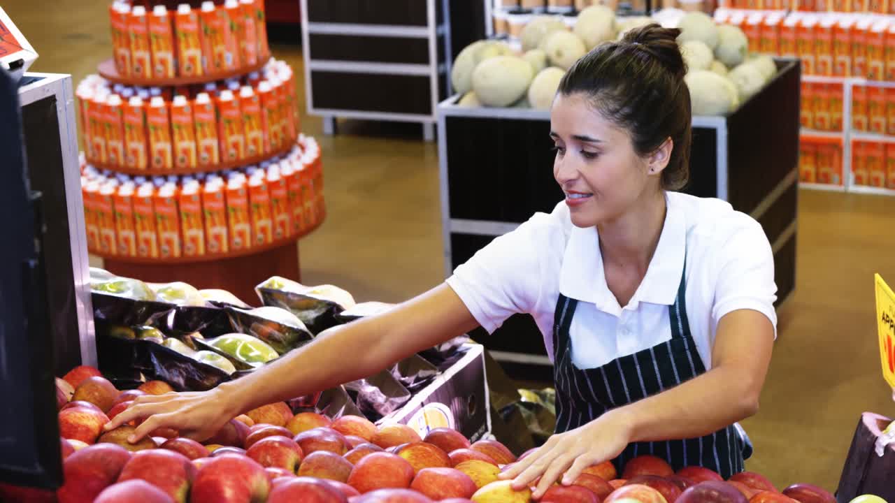 personal femenino organizando manzanas en la sección orgánica