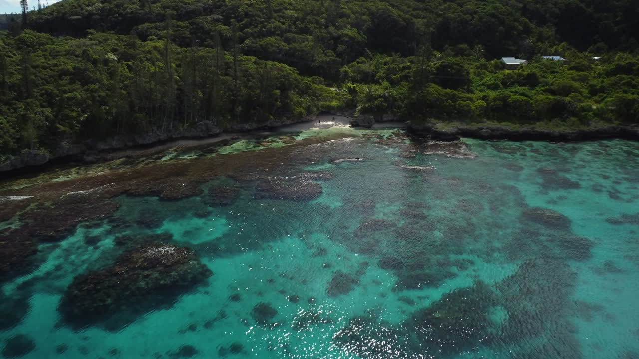 Vista aerea che si allontana dalle barriere coralline, rivelando la costa dell'isola di Maré, in Nuova Caledonia - ripresa aerea con drone, allontanamento e panoramica.