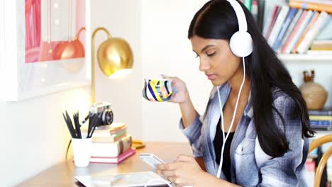 woman using mobile phone while having cup of coffee