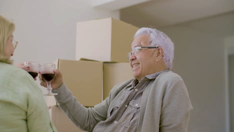 senior couple drinking wine on floor after moving to new house