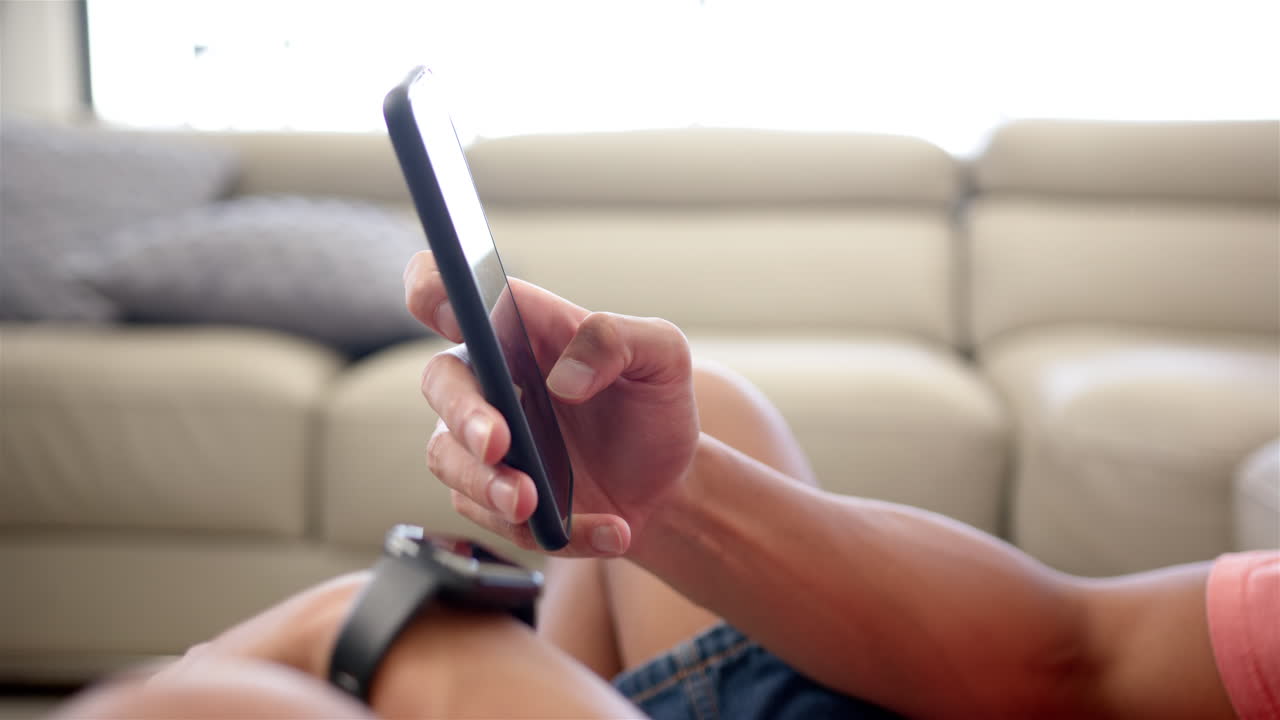 한 젊은이가 집에서 소파에서 스마트폰을 사용하고 있다.