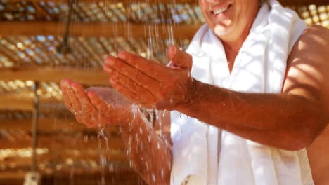 Man-washing-hands-from-shower-in-cottage-during-safari-vacation-4k