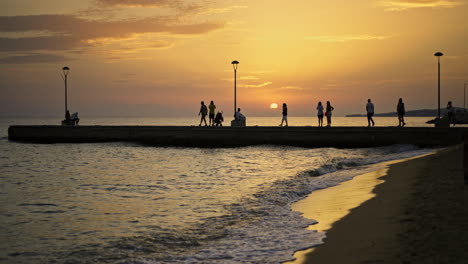 people walking on a pier at sunset