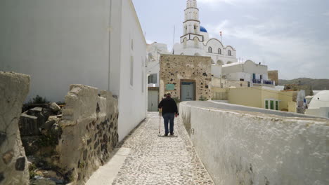 following an elderly man walking with a walking stick on a greek island