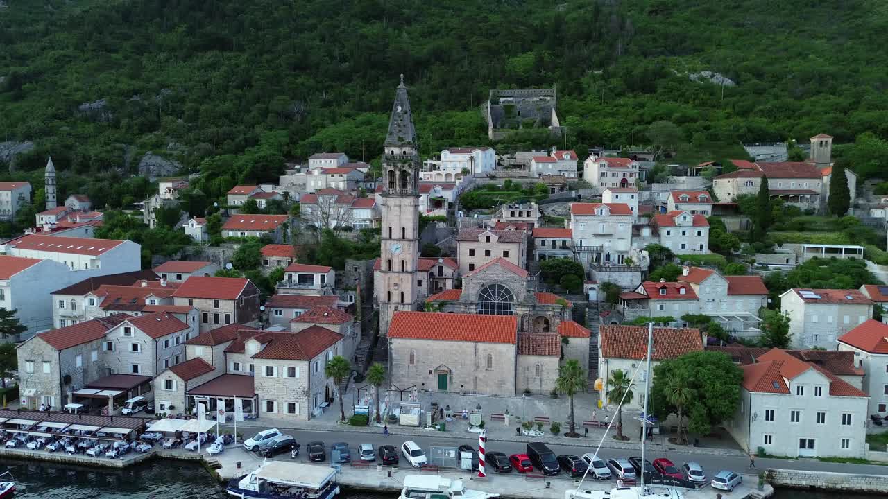 Perast village on bay of Kotor, Saint Nicholas catholic church bell tower, aerial establishing shot