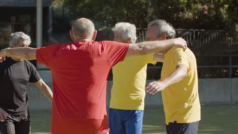 felices jugadores de fútbol senior celebrando la victoria, saltando y abrazándose en el campo