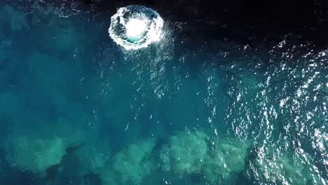 plano cenital sobre un hombre en un acantilado mientras hace un frontflip y medio en las costas cristalinas de ibiza
