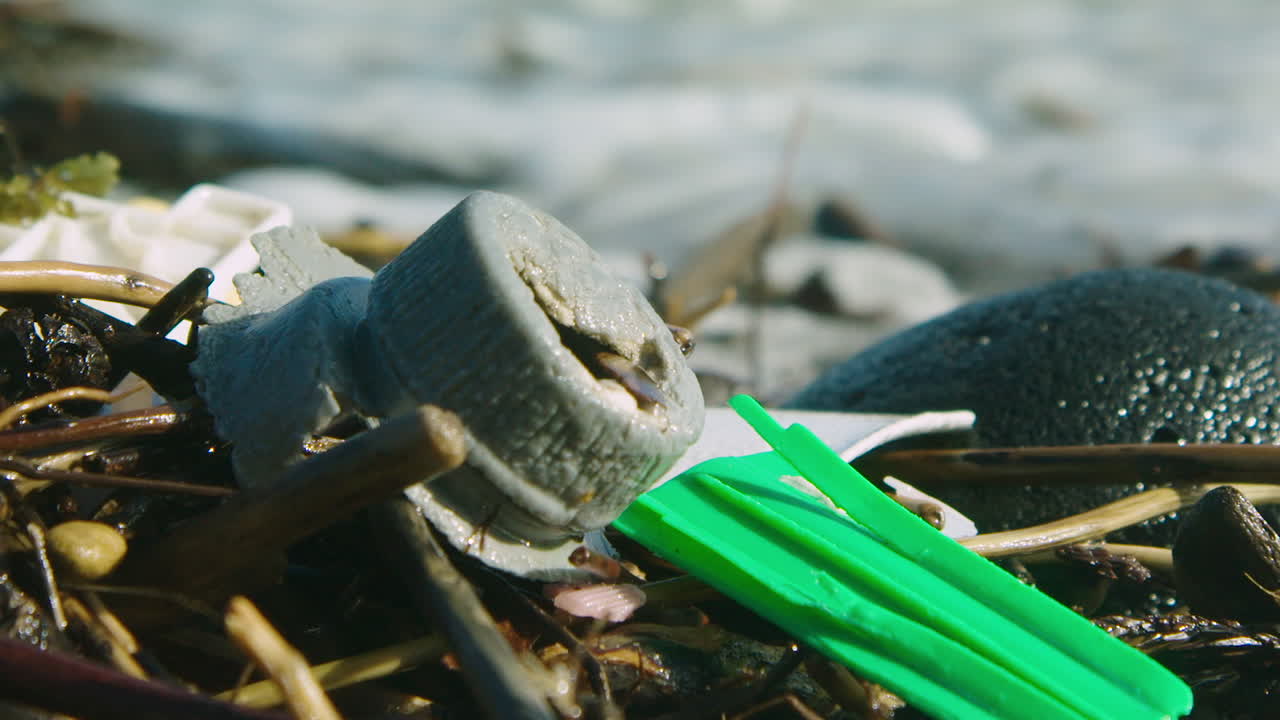impresionante toma de plástico lavado en una playa, antes de que llegue una ola y la rodee con agua espumosa