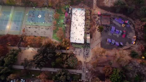 vista aérea en espiral de los campos deportivos, pista de patinaje y pista de hielo, árboles en otoño, parque araucano, santiago, chile