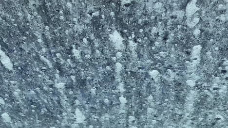 an automatic drive through car wash as viewed through the front window of a motor car creating patterns flowing down the glass