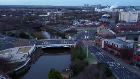 aerial early morning city street traffic commuting intersection lanes crossing curved river descend pan right