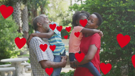 animation of hearts over happy african american multi generation family hugging in garden