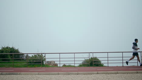 sporty guy running park in fog morning. motivated athlete training jogging track